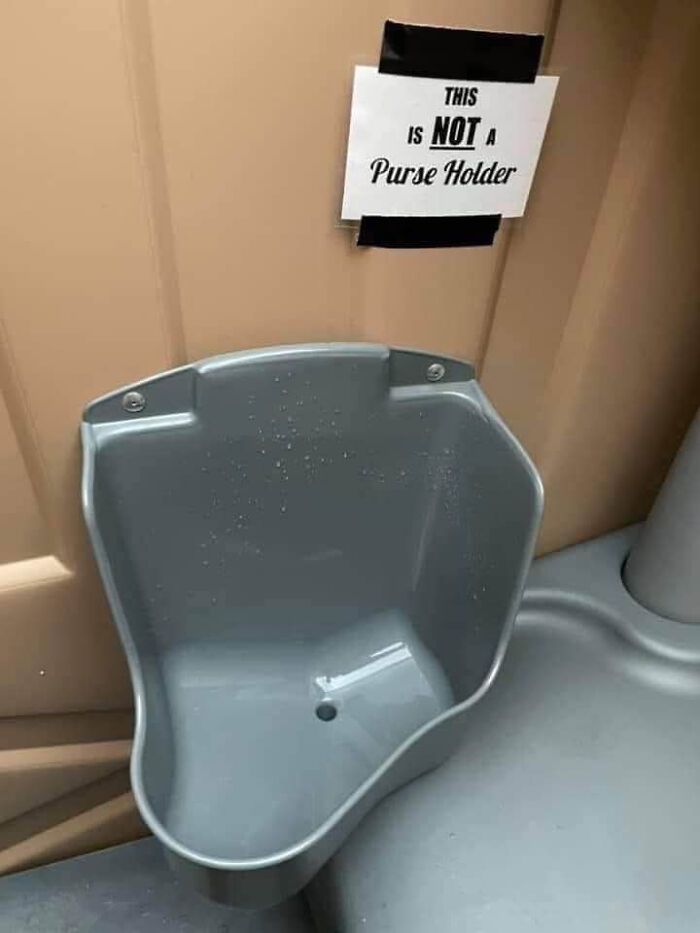 Humorous sign above a basin reads this is not a purse holder, funny sign that made people laugh or do a double take.
