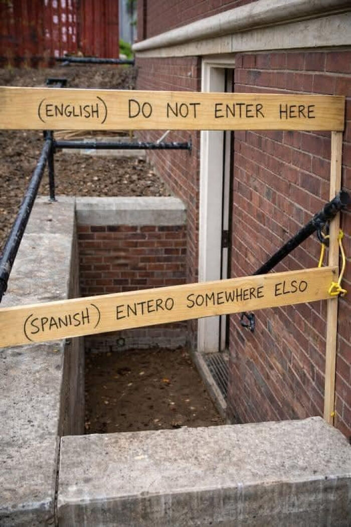 Humorous warning signs in English and Spanish blocking entrance to a basement, making people laugh or double take.
