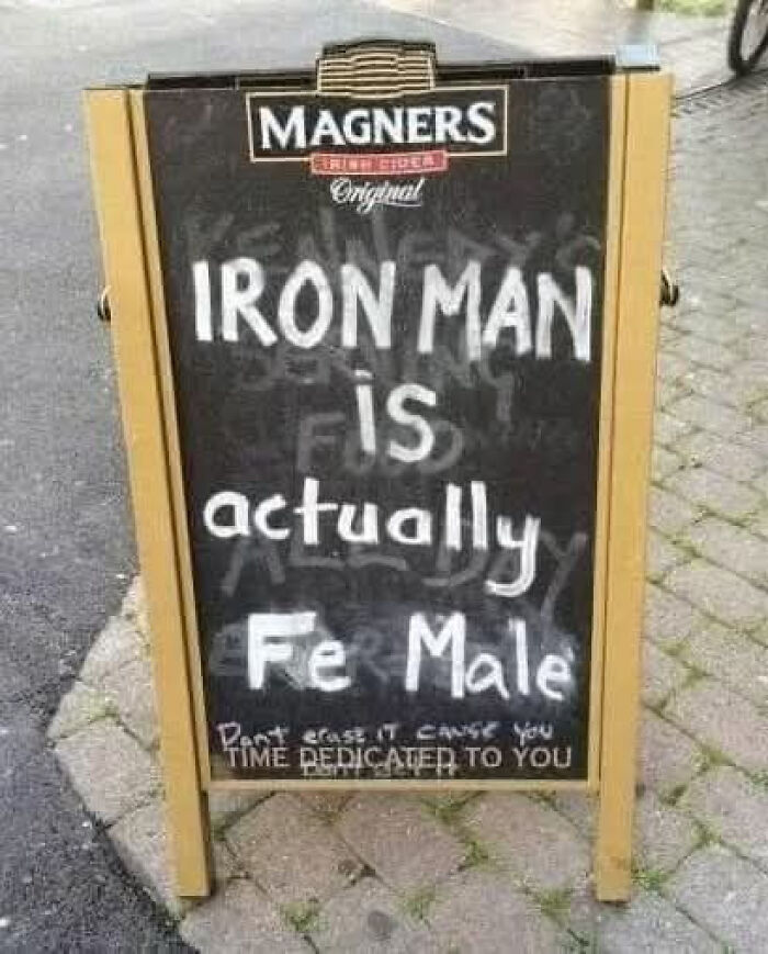 Funny pub chalkboard sign with a chemistry joke about Iron Man made people laugh or do a double take outdoors.