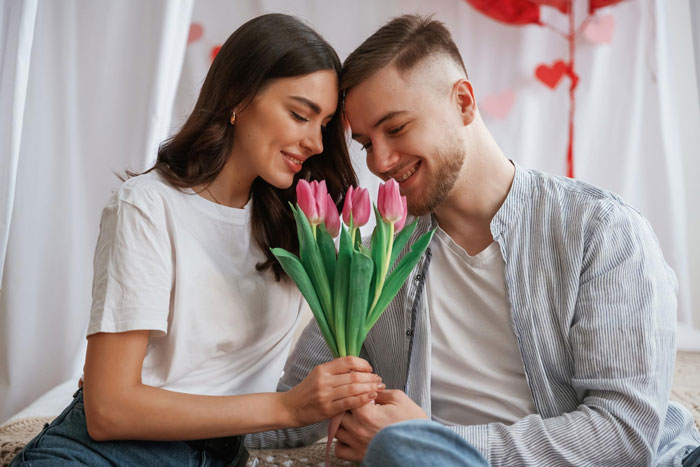 Couple smiling and holding pink tulip flowers, highlighting the moment of gave boyfriend flowers and a sexist uncle context.