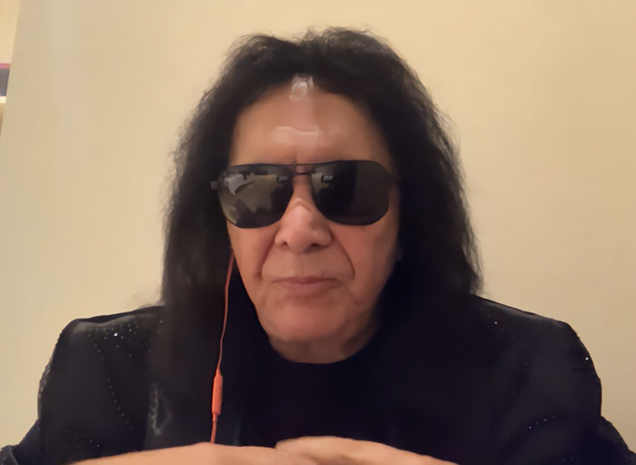 Gene Simmons wearing sunglasses and black jacket during a video call discussing Adam Sandler and internet reactions.