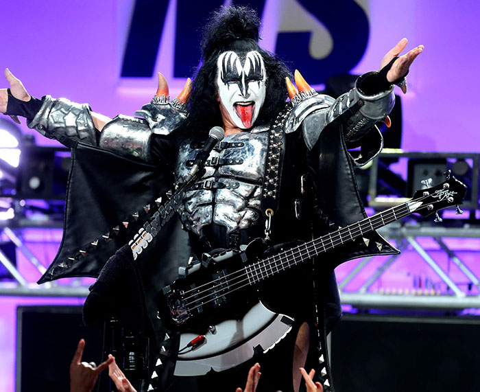 Gene Simmons performing on stage in iconic makeup and armor, sparking internet buzz about Adam Sandler.