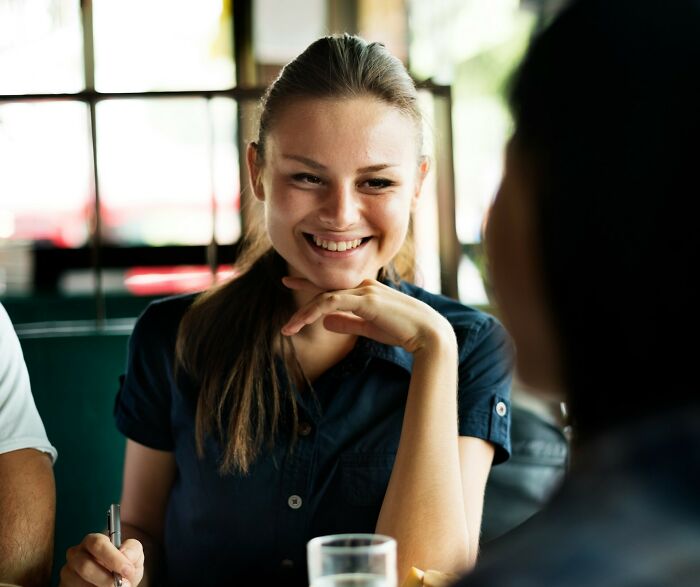 Young woman smiling confidently while talking, showcasing how amazing women brilliantly shut down men’s creepy advances.