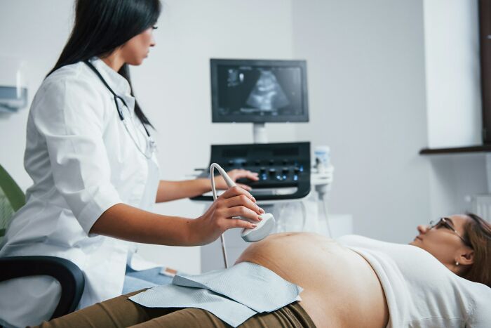 Doctor performing ultrasound on pregnant woman in medical room, highlighting brain malfunction as hidden ER visit issue.