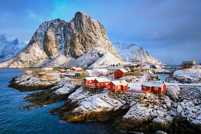 Scenic coastal village by snowy mountains illustrating 32 truths sadly vanished from people's home countries.