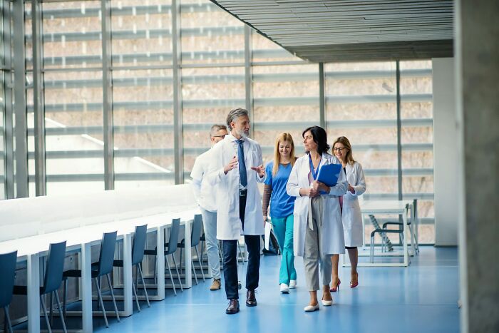 Group of medical professionals walking and discussing in a bright hospital corridor, illustrating moments people destroyed their lives.