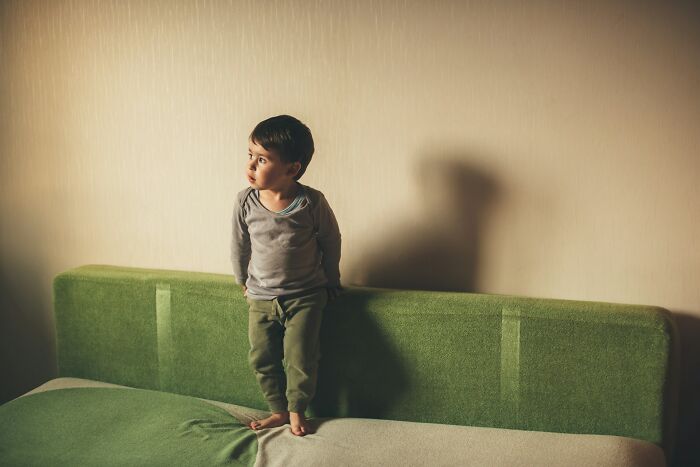 Young boy standing on a green couch, symbolizing family struggles and the challenges of forgiving a cheating spouse.