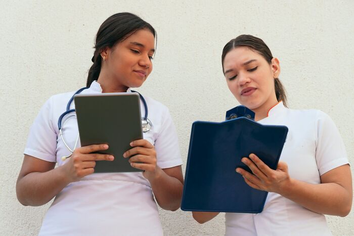 Two medical professionals reviewing notes on a tablet and clipboard illustrating moments people destroyed their lives.