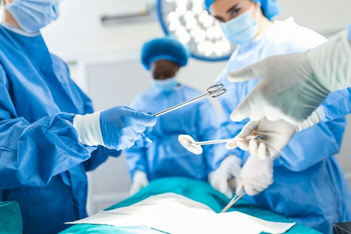 Surgeons in blue scrubs and gloves performing a complex operation, depicting one of the scariest experiences.