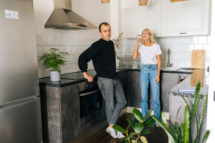 Couple in kitchen with boyfriend upset after letting girlfriend use his apartment to catch up with her ex.