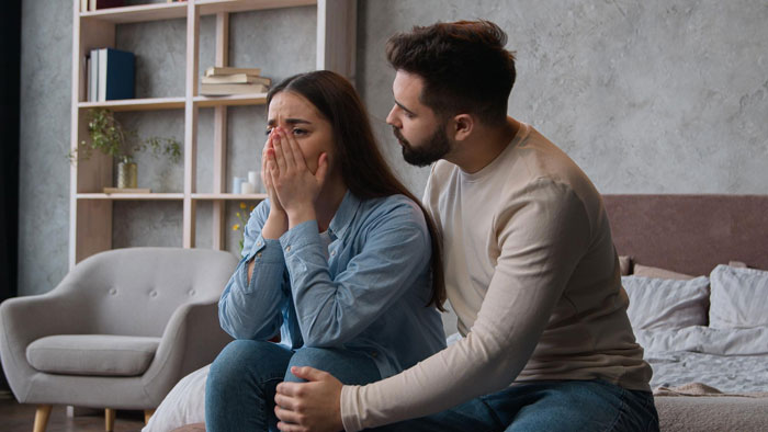 Young man comforts upset girlfriend in a tense moment, reflecting conflicts about an open relationship and family reactions.