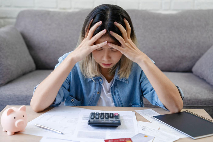 Young woman stressed at home calculating bills with a calculator in a potential gold digger test situation.