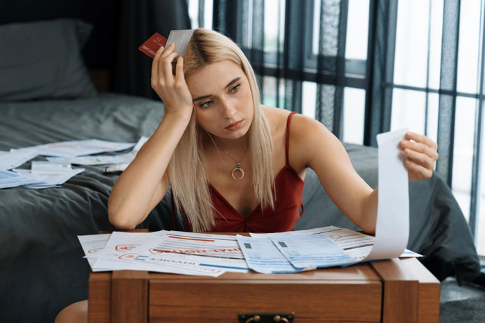 Young woman holding credit cards and bills, looking stressed in a gold digger test situation at home.