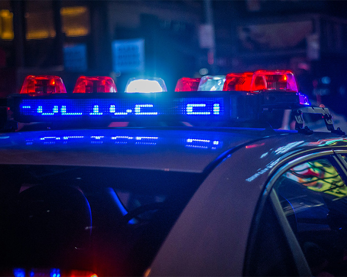 Police car lights flashing at night in downtown LA near a grisly scene after a man lost his life removing a package.