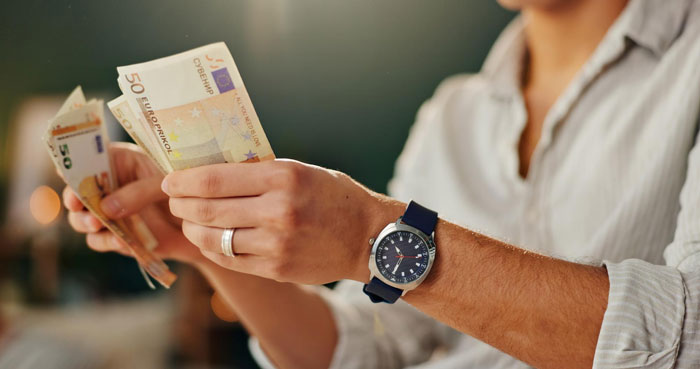 Person wearing a watch and counting euros, illustrating entitled freeloaders treating a generous friend like an ATM concept.