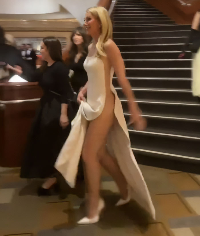 Gwyneth Paltrow backstage in a racy Oscars dress with an aide reacting awkwardly on a stairway at the venue.
