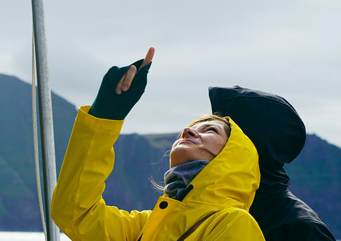 Person in yellow jacket pointing upward outdoors with partner nearby, illustrating seemingly harmless things partners do that drive people insane.