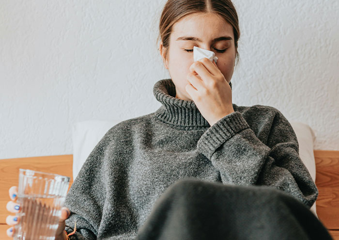Person feeling upset and holding a tissue, illustrating how seemingly harmless partner habits can drive people insane.