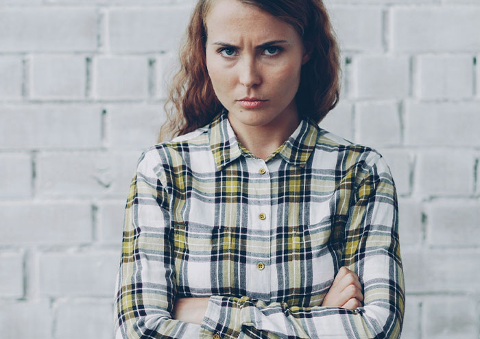 Young woman with arms crossed and an annoyed expression, illustrating partner behaviors that drive people insane
