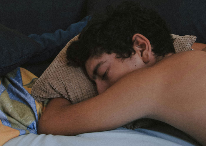 Young man sleeping on bed, illustrating seemingly harmless things partners do that still drive people insane in relationships.