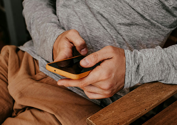 Close-up of person holding smartphone wearing casual clothes, illustrating seemingly harmless things partners do that drive others insane.