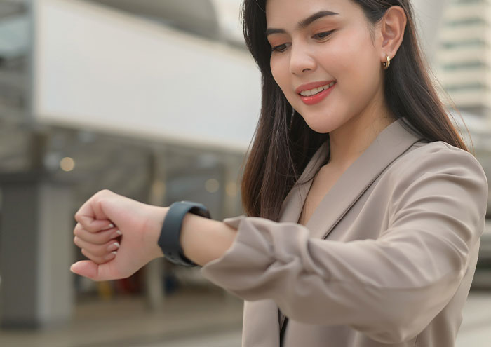 Young woman smiling while checking her smartwatch outdoors, illustrating seemingly harmless things partners do that drive people insane.