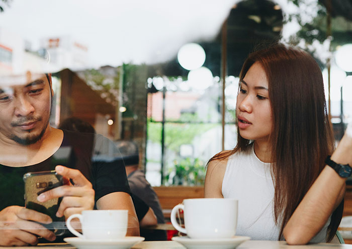 Couple having a tense conversation in a cafe, illustrating seemingly harmless things partners do that drive people insane.