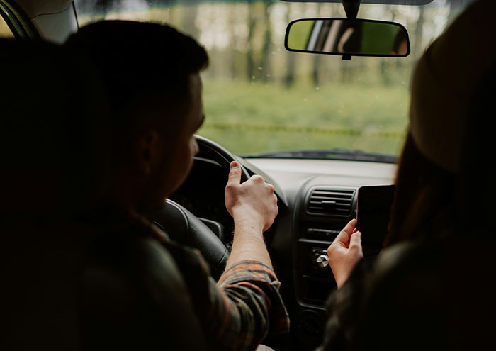 Couple in a car showing seemingly harmless things partners do that still drive people insane during a drive.
