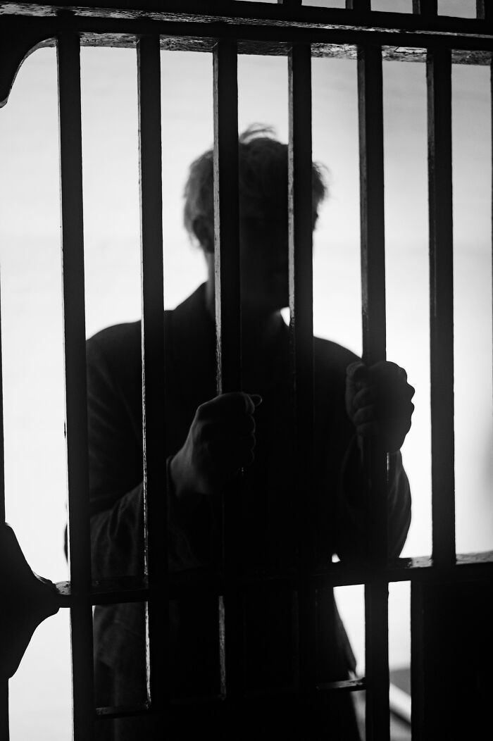 Silhouette of a person gripping prison bars, representing moments when people destroyed their own lives in an instant.