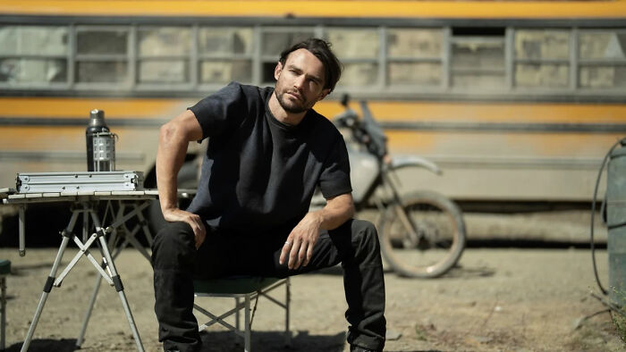 Man sitting outside near trailer and motorcycle, symbolizing Paradise Season 2 finale&rsquo;s confusing twist explained by creators.