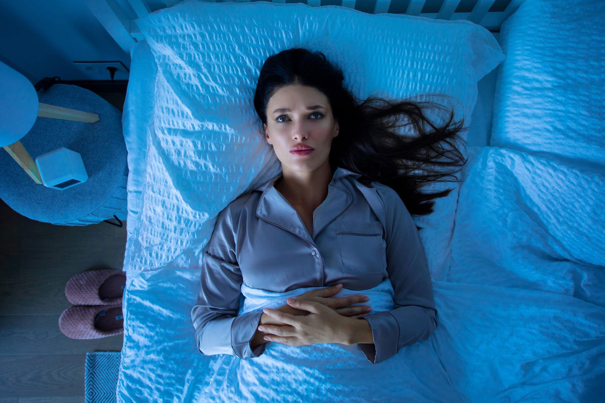 Worried wife lying awake in bed at night, feeling uneasy after hearing moaning and seeing husband shirtless with bestie naked.