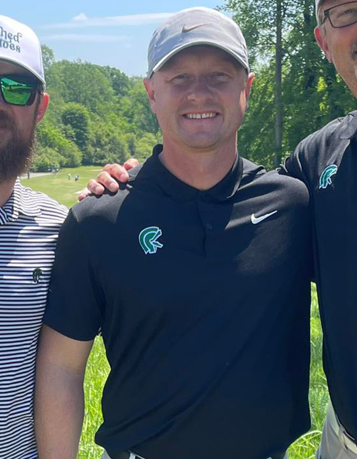 Man wearing grey cap and black polo shirt outdoors with friends, related to teacher loses life prank and teens arrested case.