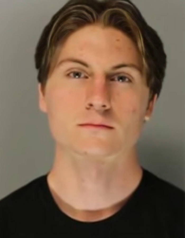 Young man with short brown hair and serious expression wearing a black shirt, linked to teacher loses his life prank case.