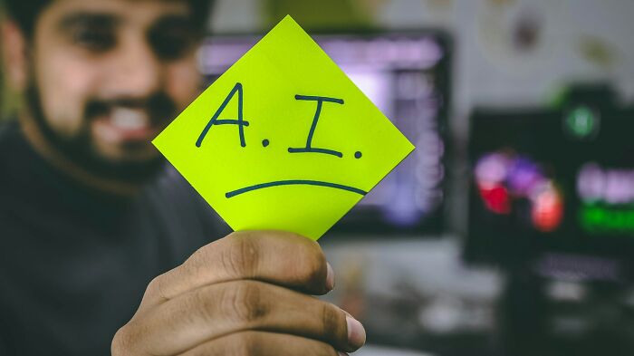 Person holding a sticky note with A.I. written on it, highlighting shaky industries vulnerable to collapse.