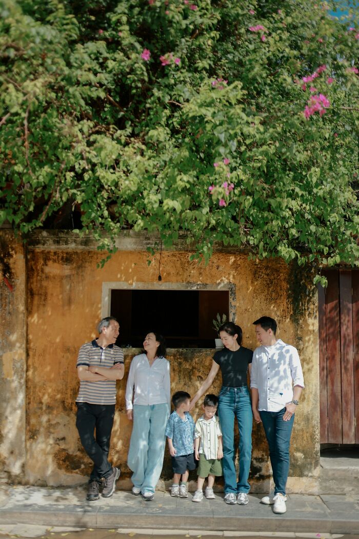 Multigenerational family standing outdoors by an old wall and greenery, showcasing unusual family traditions together.
