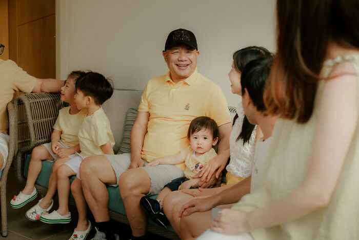 A family gathered in a living room, smiling and interacting, showcasing unique and weird family traditions together.