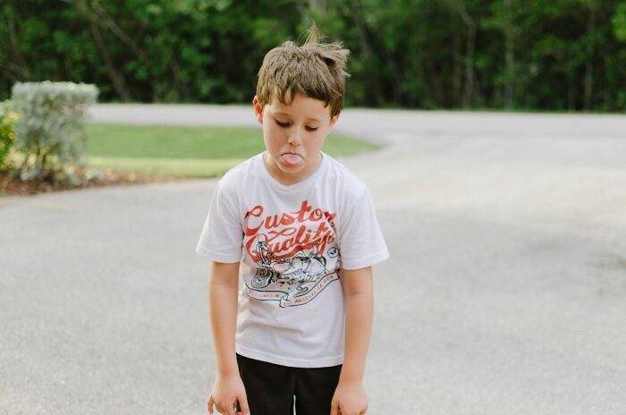 Young boy sticking out his tongue outdoors, capturing a moment of playful comebacks and on point expressions.