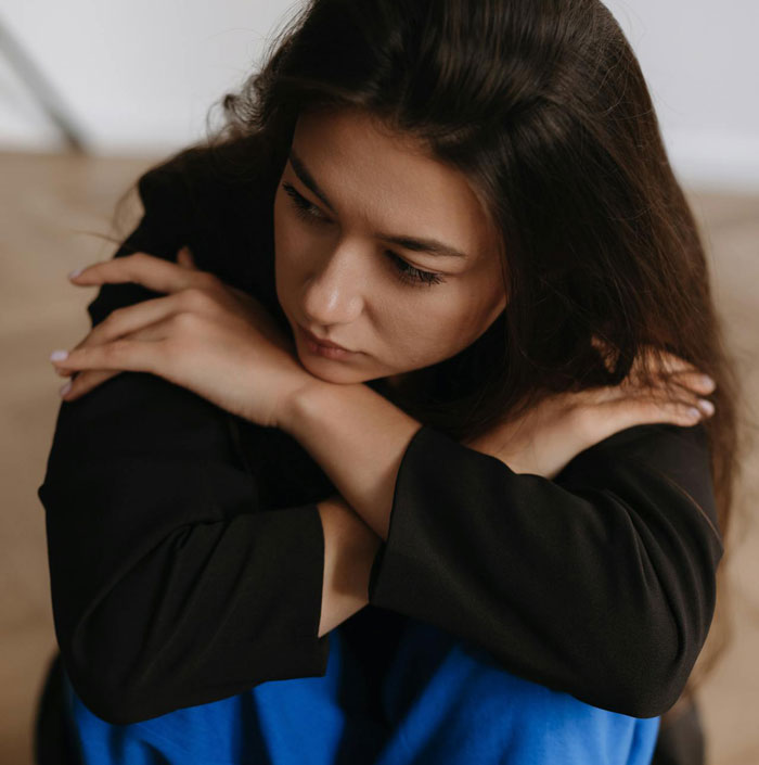 Woman in black shirt looking down, appearing sad and thoughtful after uncovering husband's affair and life changes.