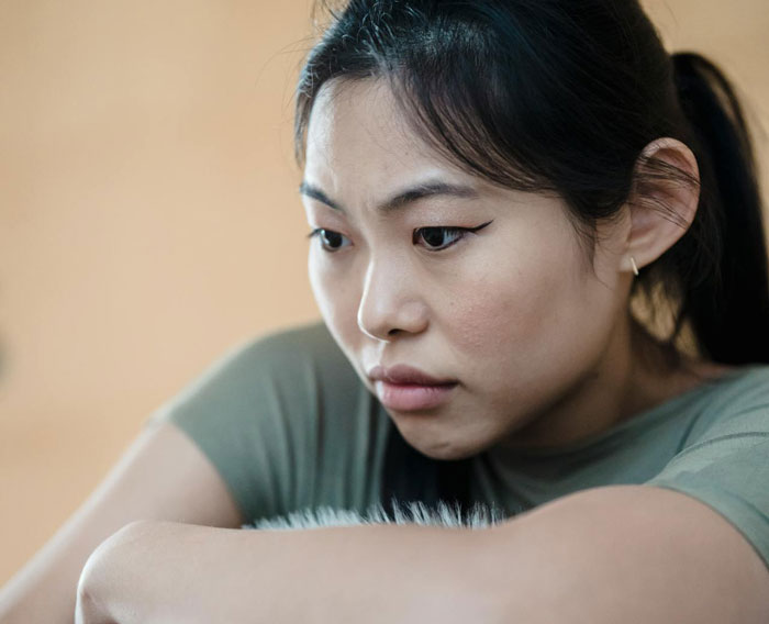 Young woman in green shirt looking contemplative, reflecting on husband's affair and life changes after accident.
