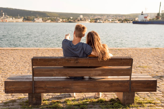 Couple sitting on a bench by the water, wife realizing hubby downgraded from gorgeous to kind, feeling crushed. Couple sitting on a bench by the water, wife realizing hubby downgraded from gorgeous to kind, feeling crushed.