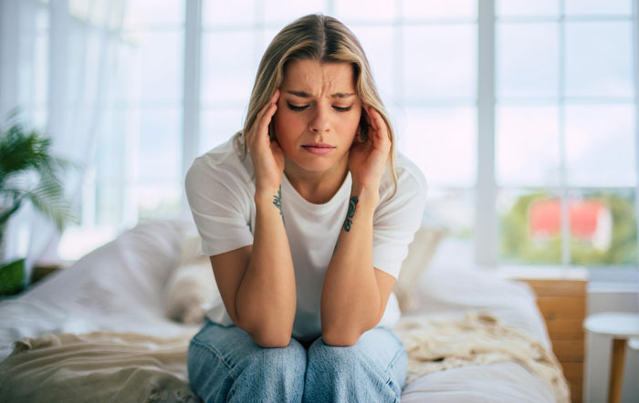 Worried wife sitting on bed holding head, stressed about husband wanting to father his ex's child and dark secret revealed