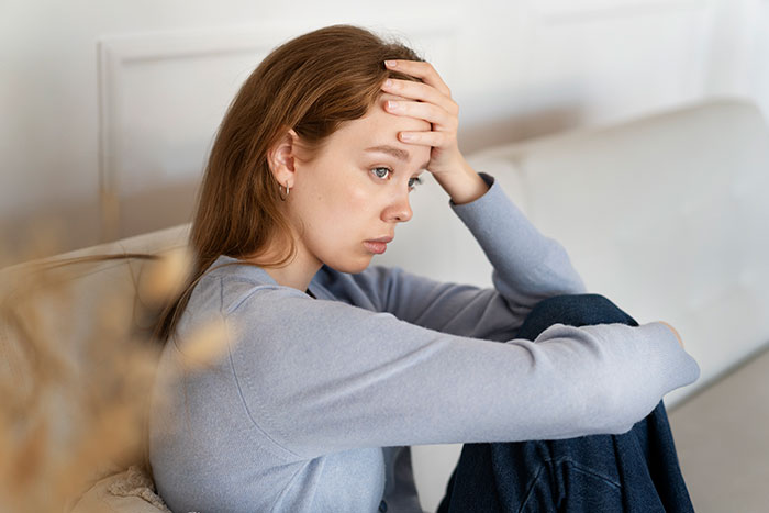 Worried woman sitting on couch, reflecting on husband&rsquo;s obsession with her sister&rsquo;s weight and uncovering revealing texts.