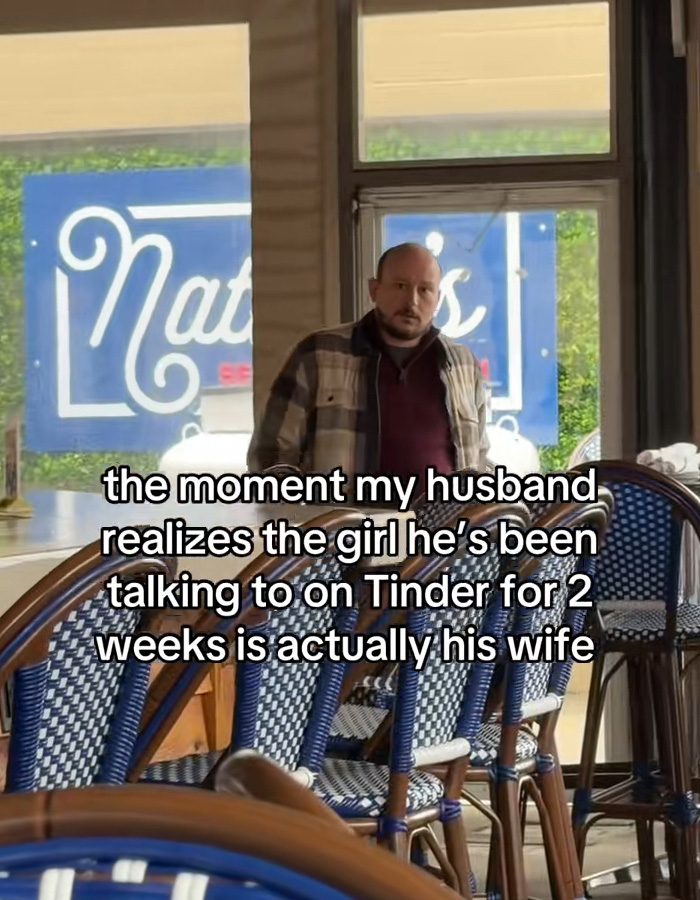 Man in a plaid shirt standing inside a cafe, surprised after realizing the woman he messaged on Tinder is his wife.
