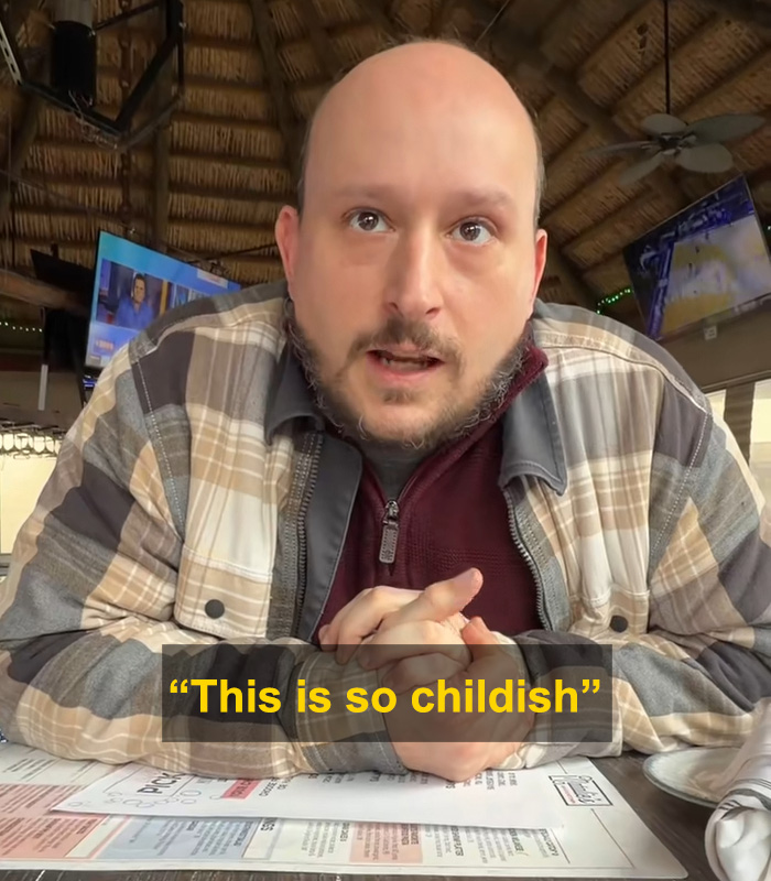 Man in casual plaid jacket and maroon shirt reacting with surprise, relating to husband and wife messaging on Tinder.