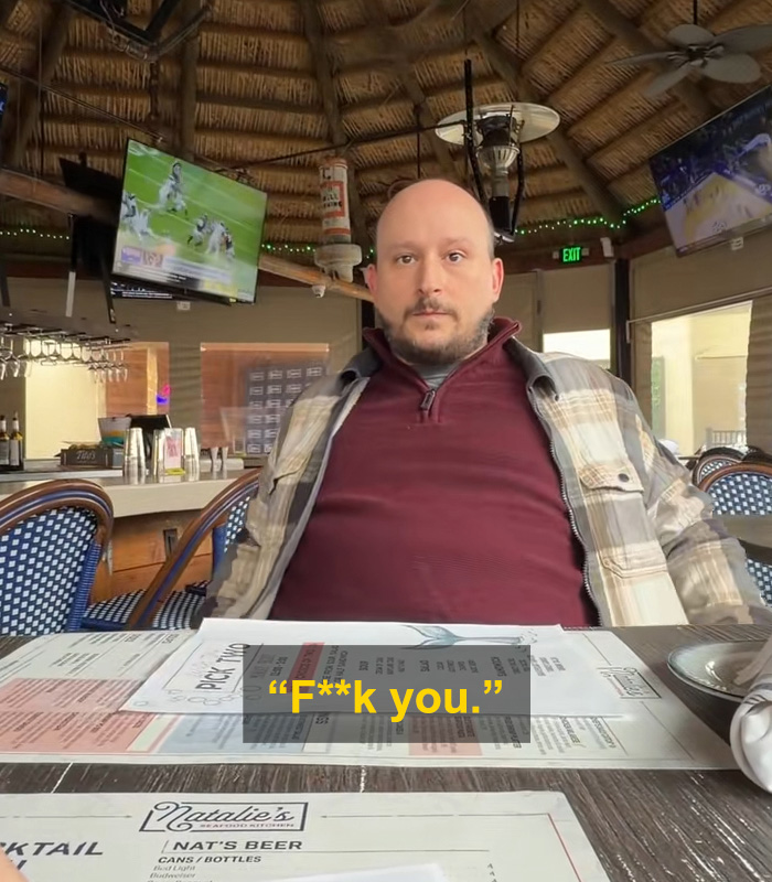 Man sitting at a table in a bar with a shocked expression, relating to husband messaging wife on Tinder SEO keywords.