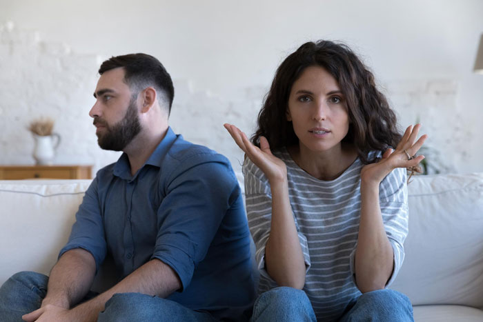 Frustrated wife questioning husband who avoids parenting duties using bathroom habit as excuse at home.