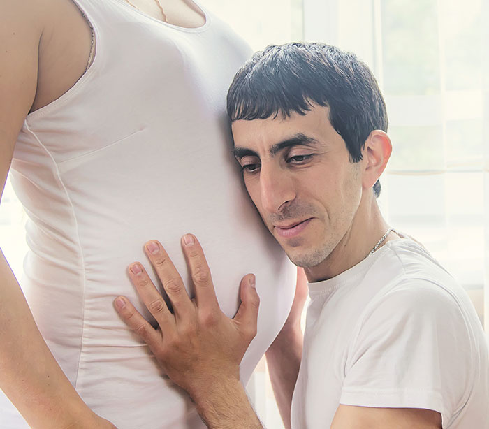 Man tenderly caring for pregnant coworker, showing kindness and support during her pregnancy at work.