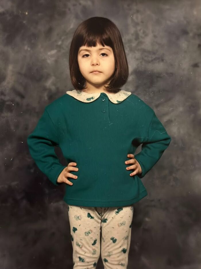 Young girl with hands on hips posing for funny school picture day fails with unimpressed expression and vintage outfit.
