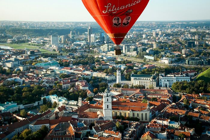 A red hot air balloon flying over a cityscape highlighting vanished truths from people's home countries.