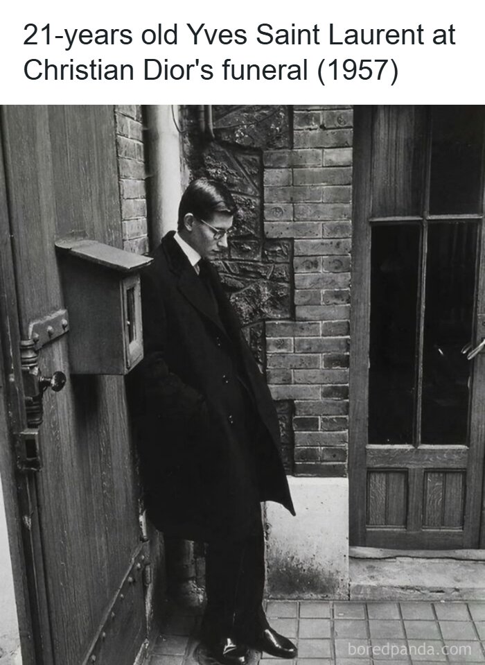 Young Yves Saint Laurent in a black coat leaning against a wall during a unique moment in history at Christian Dior’s funeral.